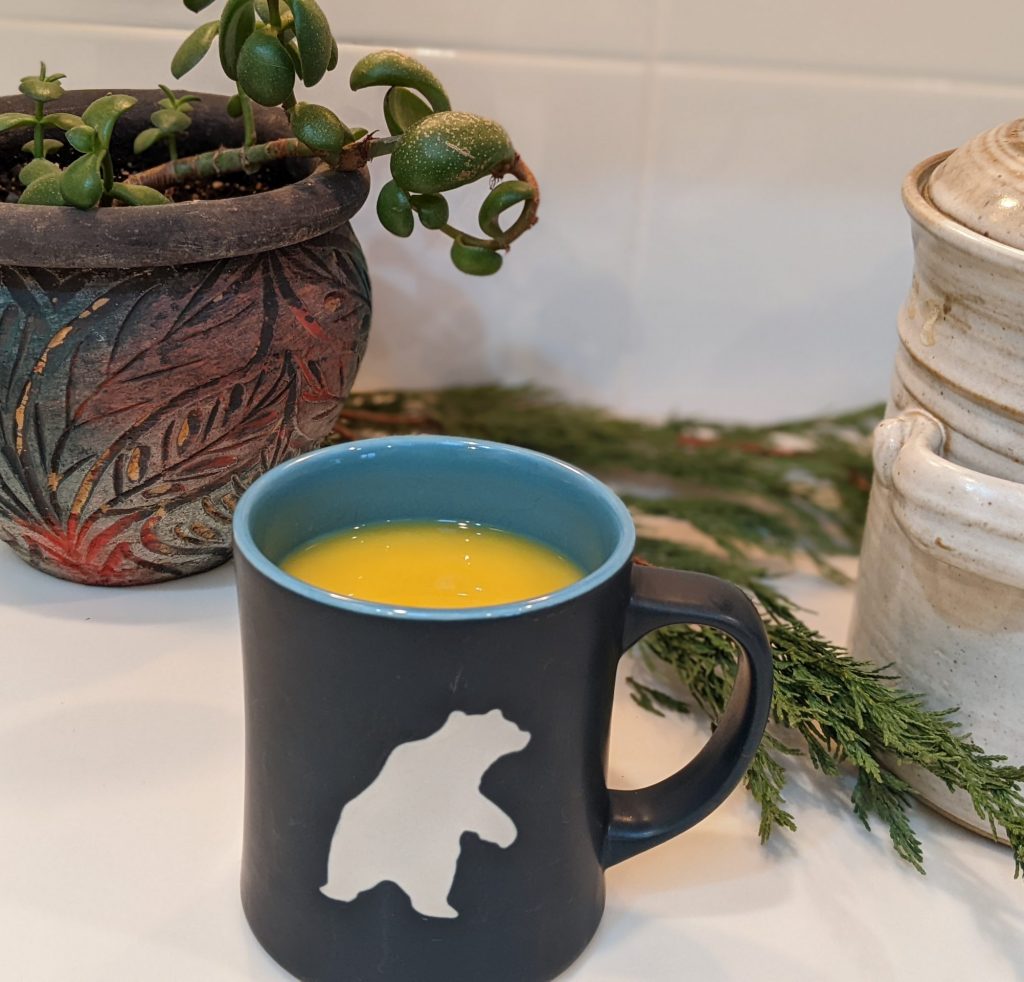 Mug of Turmeric tea for winter, potted plant and clay crock on a countertop